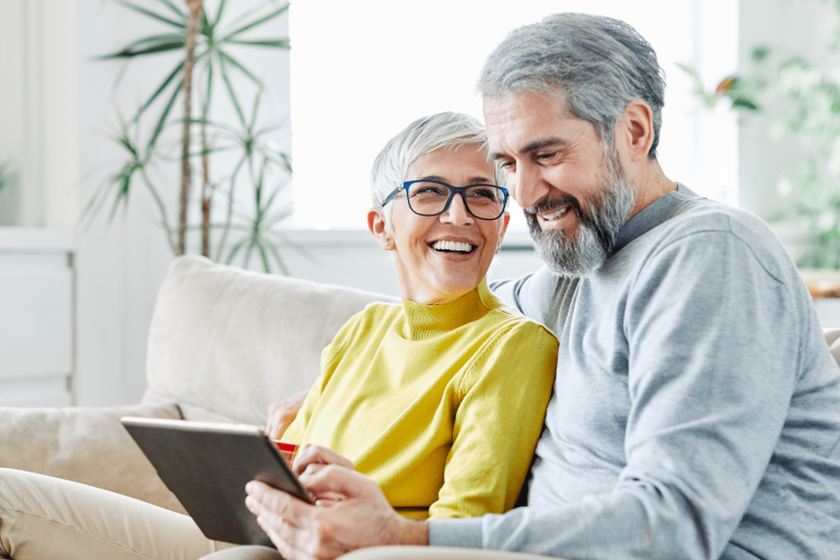 A senior couple smiling while using a laptop together.